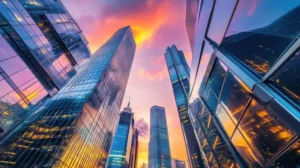 Reflective glass skyscrapers tower into a vibrant orange and purple sunset sky in Hong Kong.
