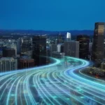 Glowing blue digital light streams wind through a city skyline at dusk beside illuminated modern skyscrapers.