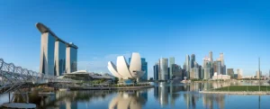 Marina Bay Sands, the ArtScience Museum, and downtown skyscrapers reflect across calm waterfront waters in Singapore.