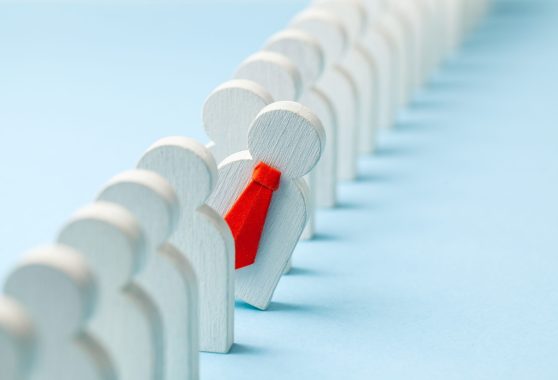 Staff recruitment. Headhunting. Many employees and the choice of a leader from the crowd. HR. A lot of white businessman and one in a red tie on a blue background